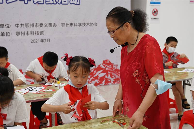 2021年7月10日，鄂州市科協(xié)組織落駕坪小學(xué)學(xué)生在鄂州市科技館開展社會(huì)主義核心價(jià)值觀系列活動(dòng)，圖為開展的紅色剪影圓夢(mèng)中華剪紙活動(dòng)，老師指導(dǎo)同學(xué)剪紙.jpg